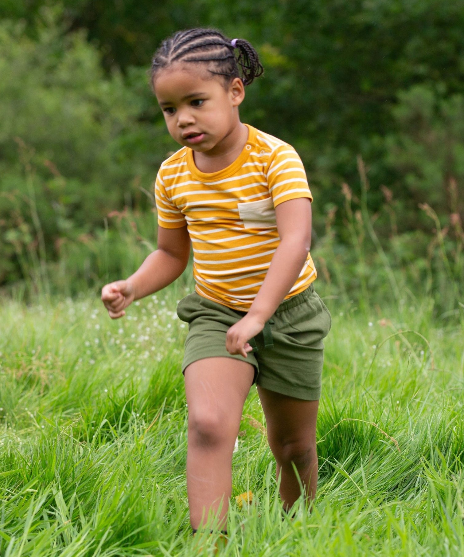 A child wearing the yellow gold striped Little Green Radicals from the Blue Organic T-Shirt Set.