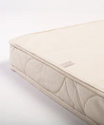 A close up of a Little Green Sheep Organic Cot Mattress Protector placed on a matress