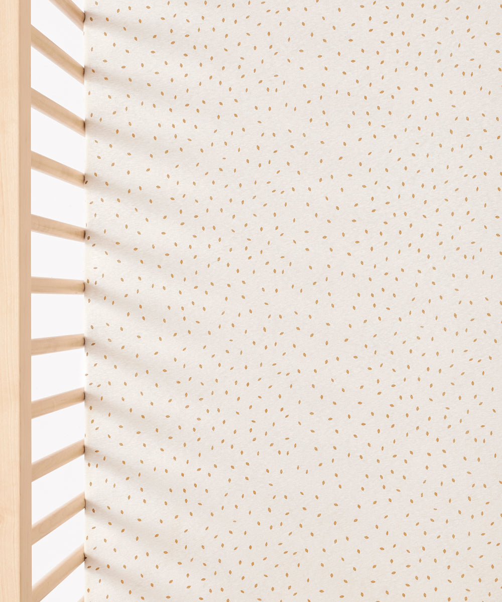A close up of the Linen rice print Little Green Sheep Organic Cot & Cot Bed Fitted Sheet in a cot
