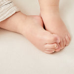 A close up of a child's feet on a Little Green Sheep Organic Cot Mattress Protector