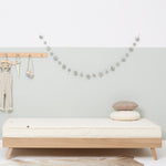 A wooden trundle bed with a Little Green Sheep atress on it. The bed is in a bedroom with walls painted white and light green.