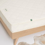A close up of a little Green Sheep mattress on a wooden bed frame 