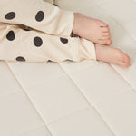 A close up of a child's feet. The child is wearing spot print pyjamas and is lying down on a Little Green Sheep mattress