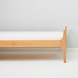Little Green Sheep Organic Single Jersey Fitted Sheet pictured on a mattress on a wooden bed