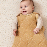 A baby ling down in a cot wearing a honey rice print Little Green Sheep baby sleeping bag