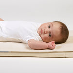 A close up of a baby lying on a Little Green Sheep Organic Moses Basket / Pram Mattress Protector