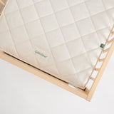 Little Green Sheep Twist Natural SnuzKot Mattress pictured in a wooden cot