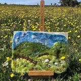 and gently rolling hills with a lovely blue sky with natural green landscape colours. There are sheep grazing i