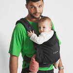 An adult carrying a baby in the Love Radius HoodieCarrier 2 - Black Forest. 