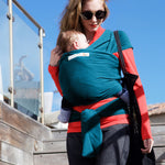Adult carrying a baby in the Love Radius Organic Baby Wrap in Retro Blue. 