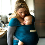 Adult carrying a baby in the Love Radius Organic Baby Wrap in Retro Blue. 