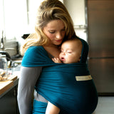 Adult carrying a baby in the Love Radius Organic Baby Wrap in Retro Blue. 