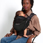 An adult carrying a baby in the Love Radius HoodieCarrier 2 - Black Forest. 