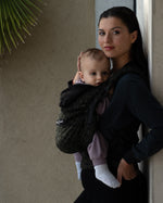 An adult carrying a baby in the Love Radius HoodieCarrier 2 - Wild Camo. 