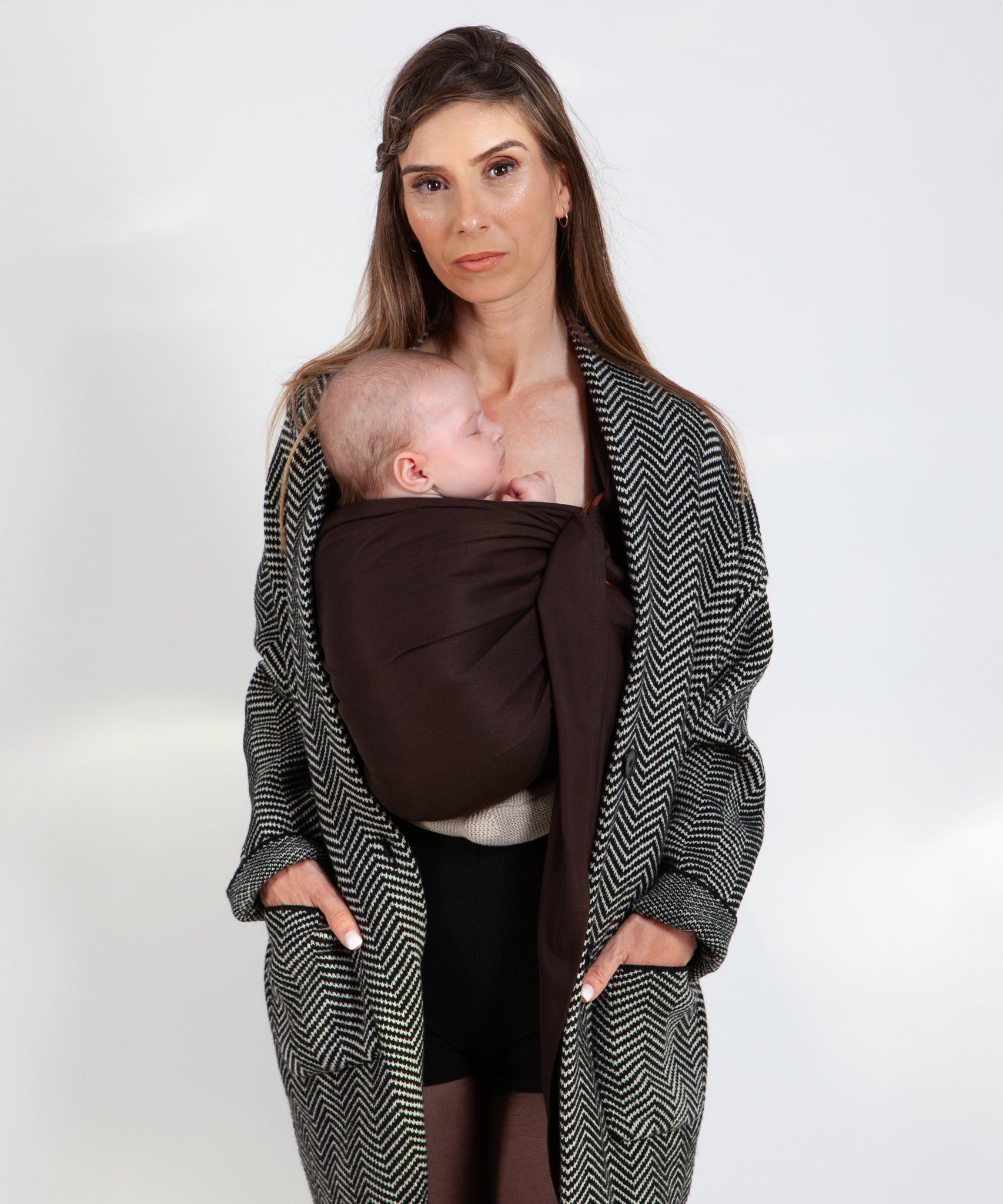 A parent wearing their baby in a espresso brown coloured Love Radius No Knot Woven Wrap. The baby is asleep. A wide range of baby wraps and carriers are available at Babipur. 