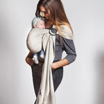 A parent wearing their baby in a white gold coloured Love Radius No Knot Woven Wrap. A wide range of baby wraps and carriers are available at Babipur. 