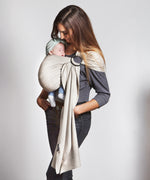 A parent wearing their baby in a white gold coloured Love Radius No Knot Woven Wrap. A wide range of baby wraps and carriers are available at Babipur. 