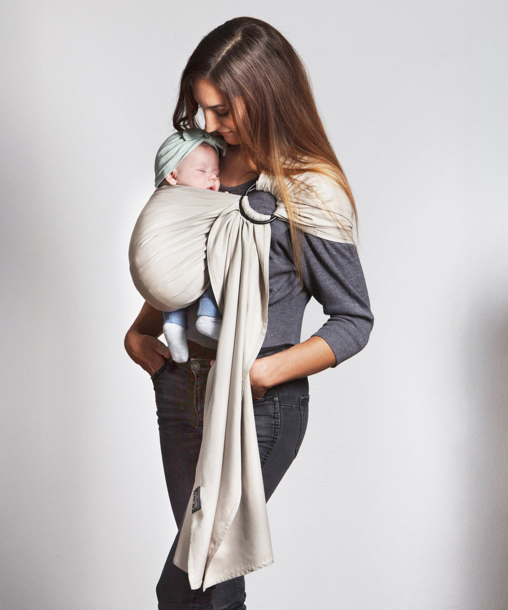 A parent wearing their baby in a white gold coloured Love Radius No Knot Woven Wrap. A wide range of baby wraps and carriers are available at Babipur. 