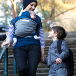 Adult carrying a baby in the Love Radius Original JPMBB Baby Wrap - peacock blue/elephant