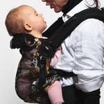 An adult carrying a baby in the Love Radius PhysioCarrier in Tiger.