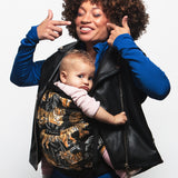 An adult carrying a baby in the Love Radius PhysioCarrier in Tiger.