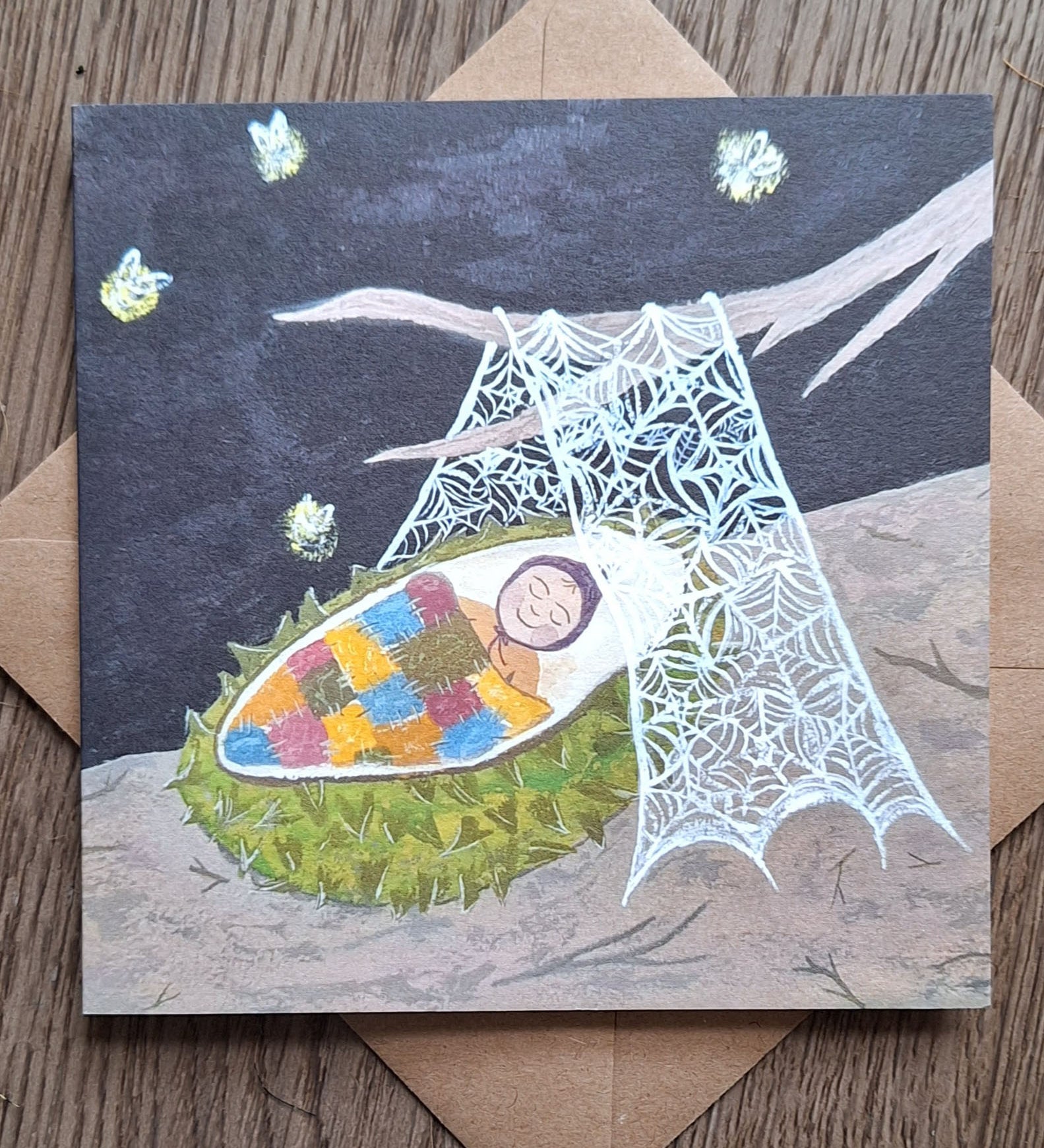 A conker baby greetings card from Lydiamae showing a illustration of a baby inside a conker shell under a spiders web in a soft drawing style