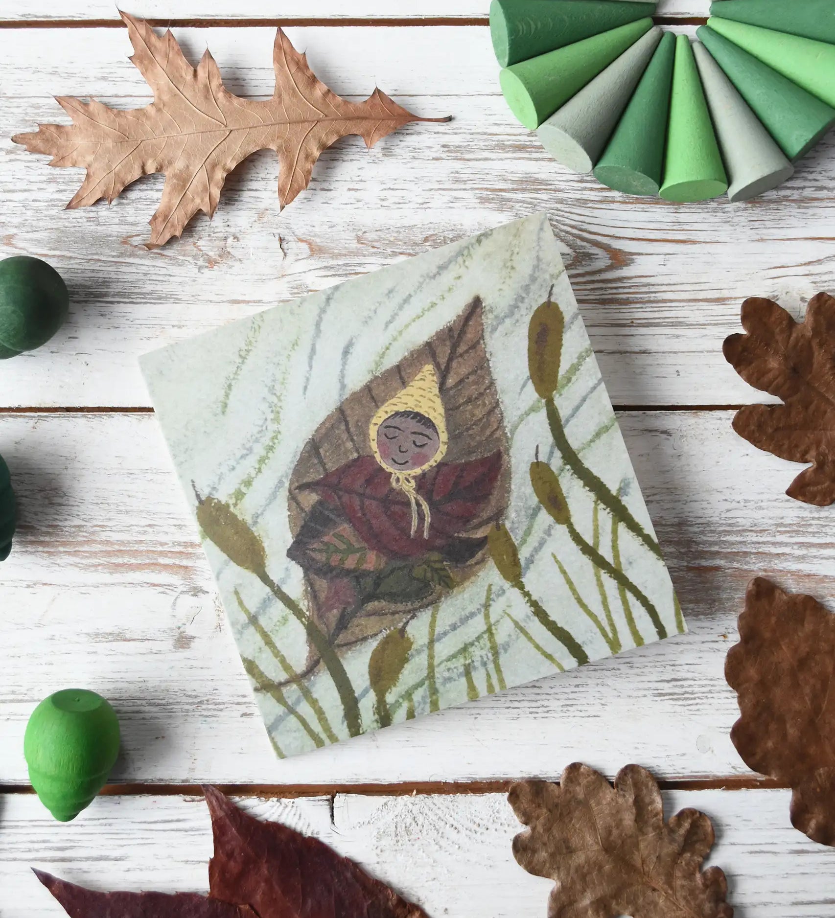  LydiaMae Leaf Baby Greetings Card placed in the centre of a flatlay with Grapat mandala pieces and dried leaves.