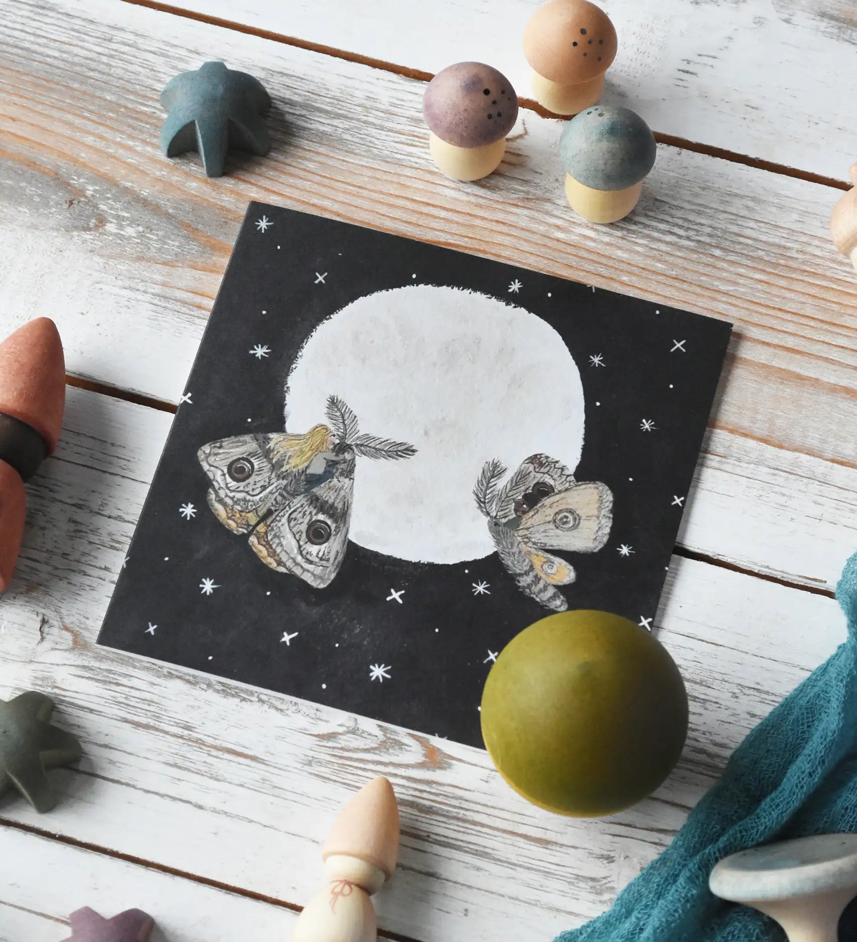 LydiaMae moths in the moonlight greetings card placed in the middle of a flatlay surrounded by pieces from the Grapat Moonlight tale play set. 