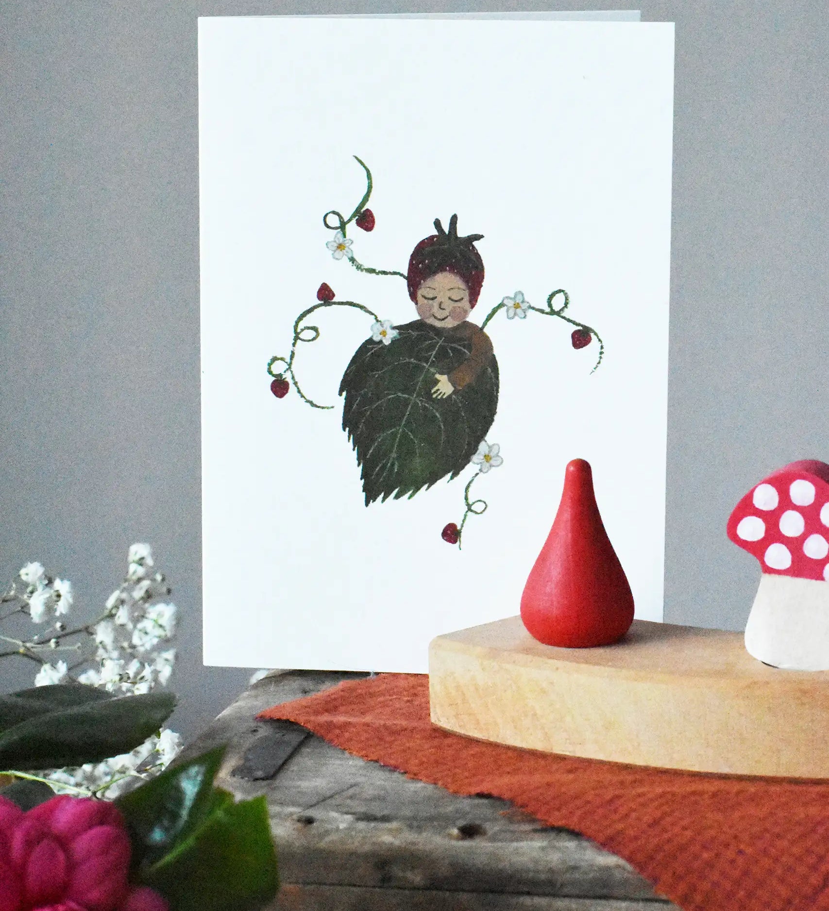  LydiaMae strawberry baby greetings card placed behind a decorated Grimm's celebration ring as part of a seasonal display. 