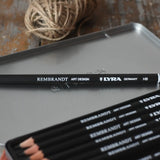 Close up of Lyra 12 drawing pencils in sizes from 6B to 4H in a metal storage tin.