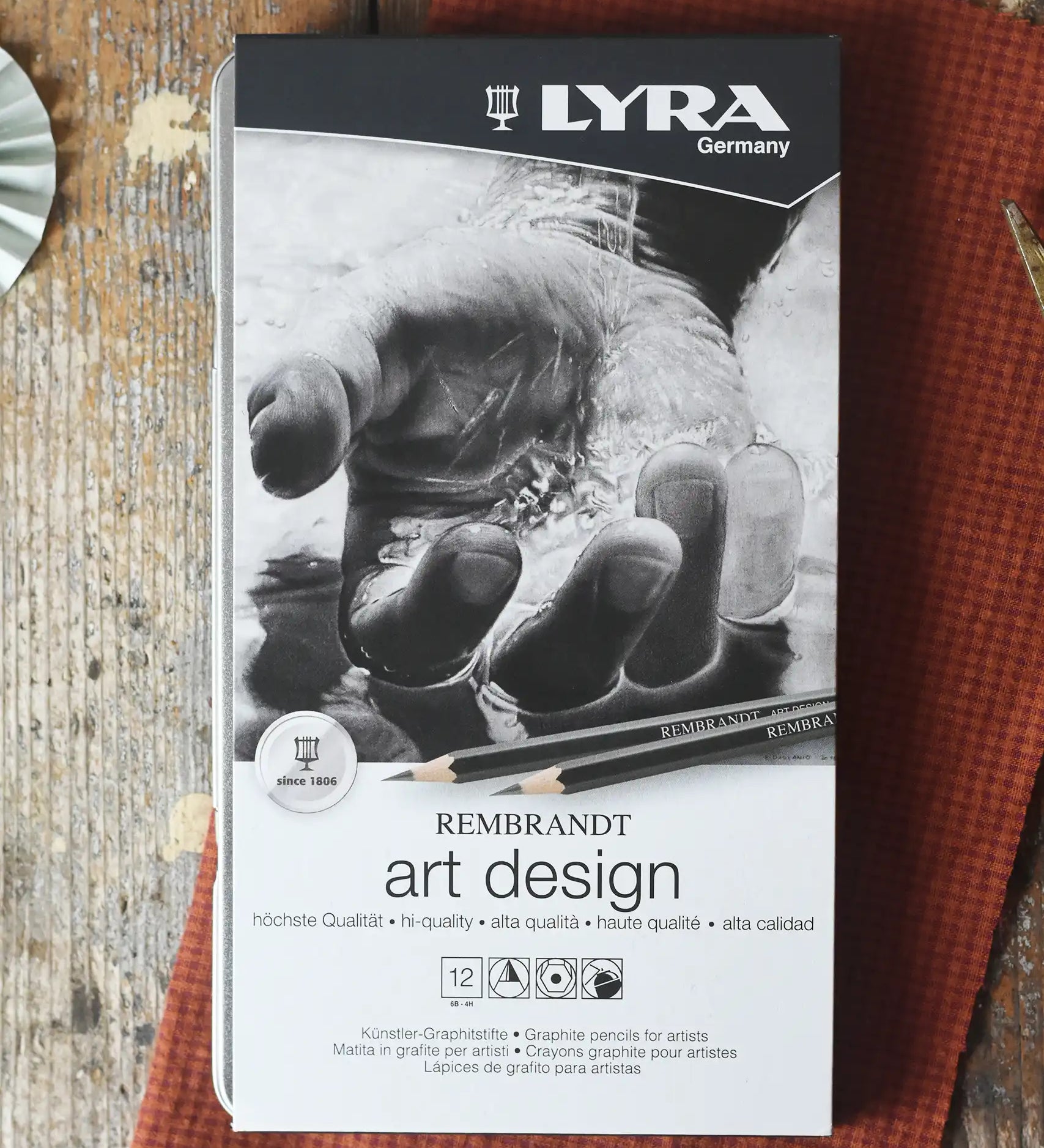 Lyra 12 drawing pencils in sizes from 6B to 4H in a metal storage tin.