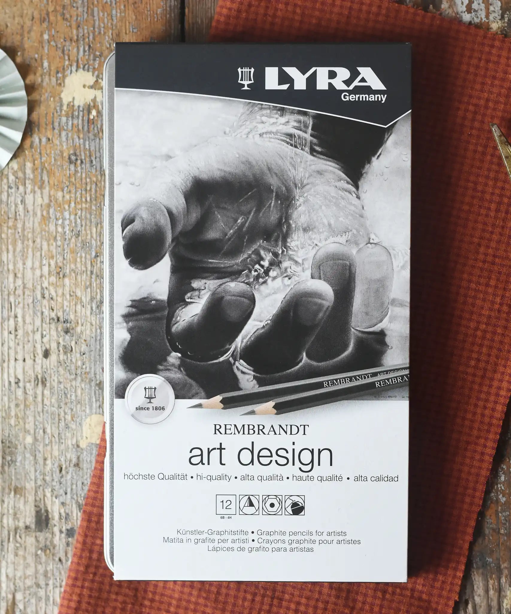 Lyra 12 drawing pencils in sizes from 6B to 4H in a metal storage tin.