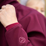 Close up of Mamalila soft shell baby wearing allrounder fitted jacket in black showing brand logo on the lower sleeve