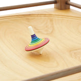 Rainbow stripe rallye spinning top on the Mader Kreiselmanufaktur Manège wooden spinning plate.