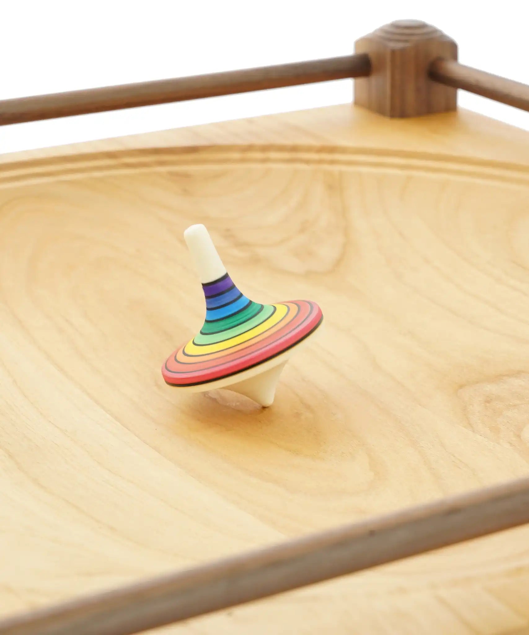 Rainbow stripe rallye spinning top on the Mader Kreiselmanufaktur Manège wooden spinning plate.