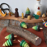 Mader Kreiselmanufaktur 5 tree spinning tops on branch placed on a wooden desk in the Babipur playroom. The trees have all been taken out of the slots and placed besides the branch.