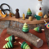 Mader Kreiselmanufaktur 5 tree spinning tops on branch placed on a wooden desk in the Babipur playroom. One is slotted into the branch the others have been laid besides it.