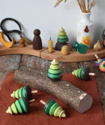 Mader Kreiselmanufaktur 5 tree spinning tops on branch placed on a wooden desk in the Babipur playroom. One is slotted into the branch the others have been laid besides it.
