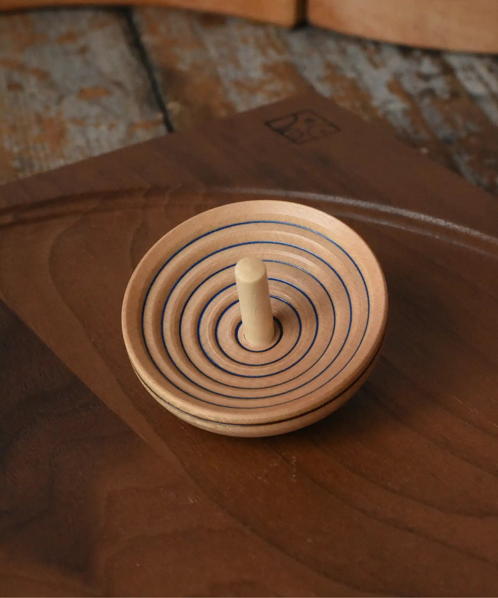 Mader UFO campanola spinning top in blue placed on a walnut spinning plate in the Babipur playroom. 