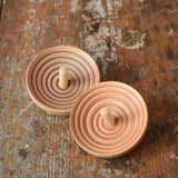 Two Mader UFO campanola spinning top in blue and red placed on a wooden desk in the Babipur playroom. 