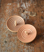 Two Mader UFO campanola spinning top in blue and red placed on a wooden desk in the Babipur playroom. 
