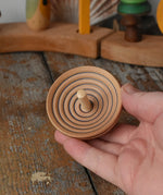 Mader UFO campanola spinning top in blue in an adult hand. 