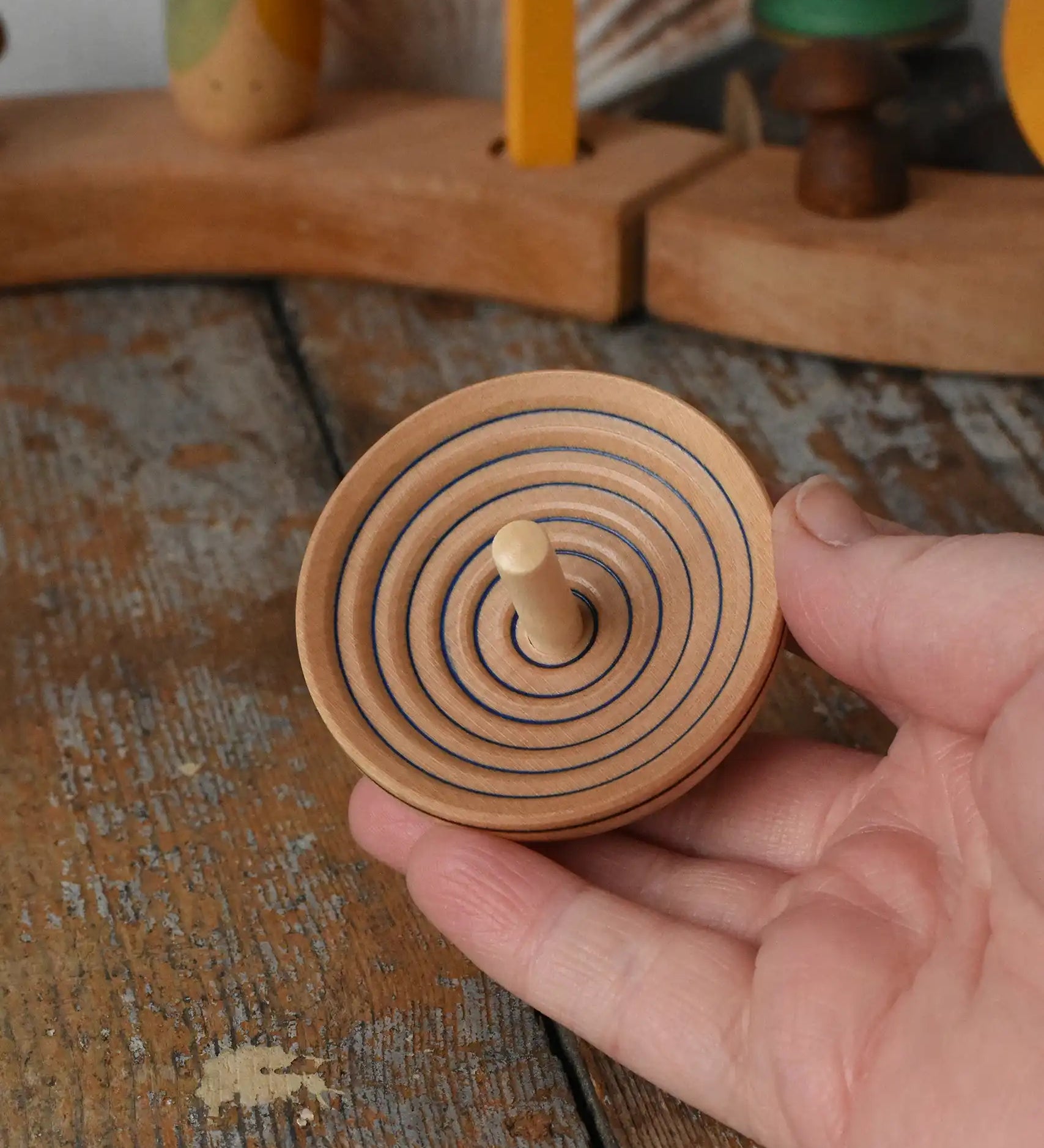 Mader UFO campanola spinning top in blue in an adult hand. 