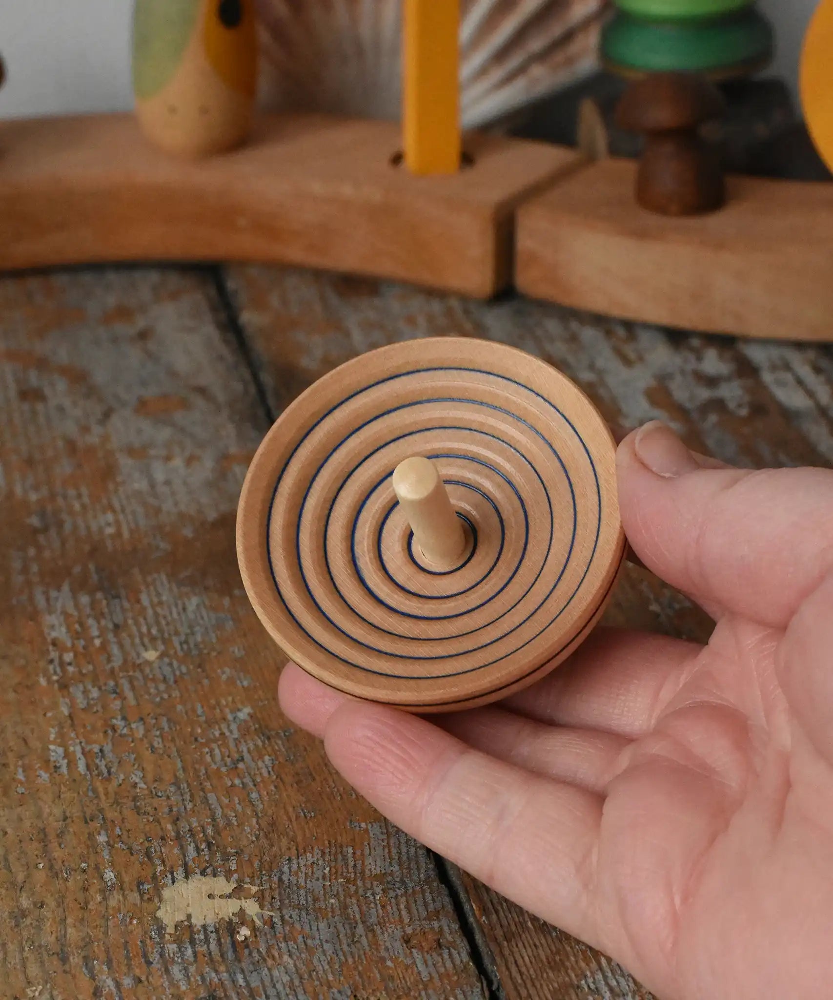 Mader UFO campanola spinning top in blue in an adult hand. 