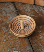 Mader UFO campanola spinning top in blue placed on a wooden desk in the Babipur playroom. 