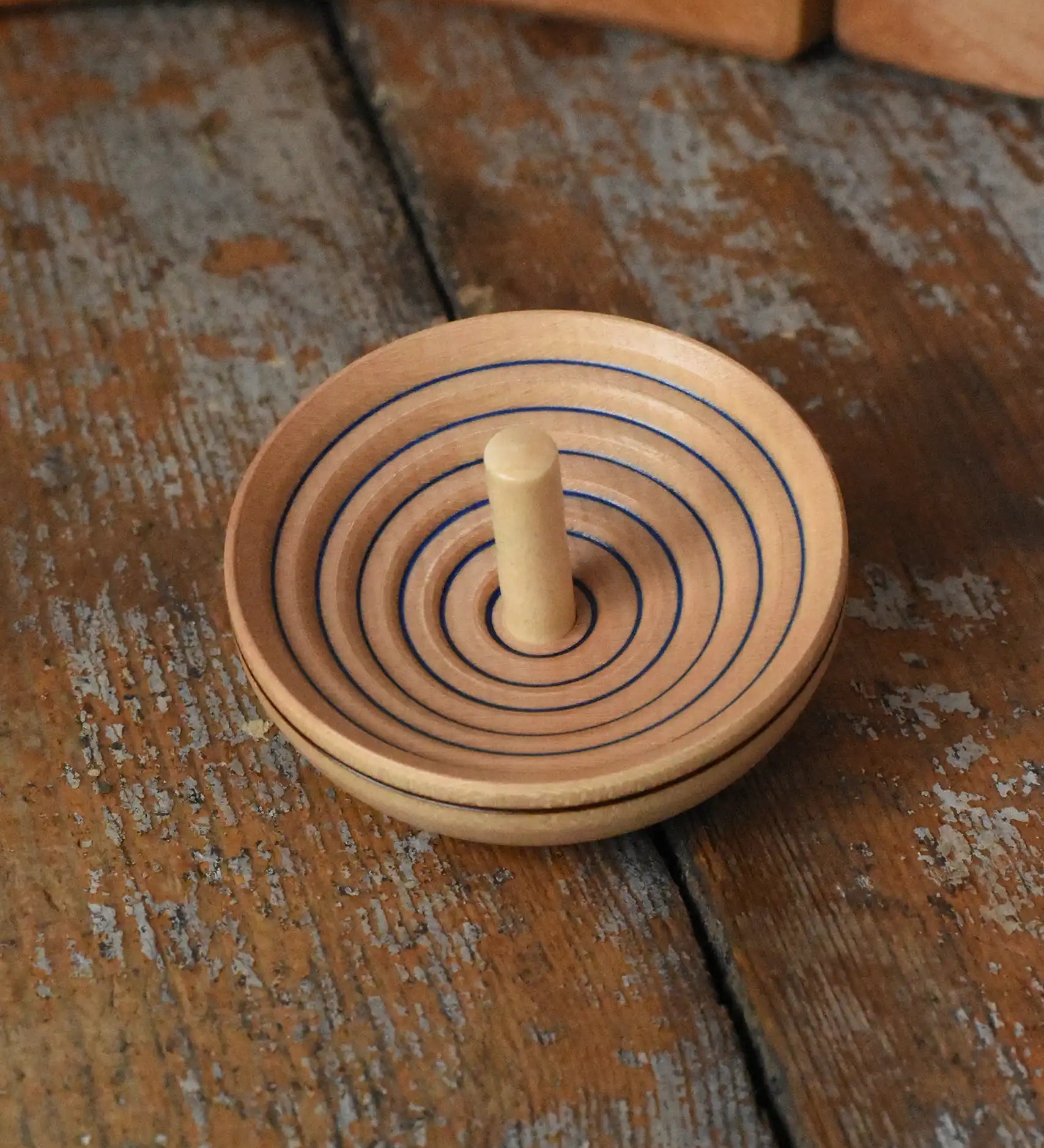 Mader UFO campanola spinning top in blue placed on a wooden desk in the Babipur playroom. 