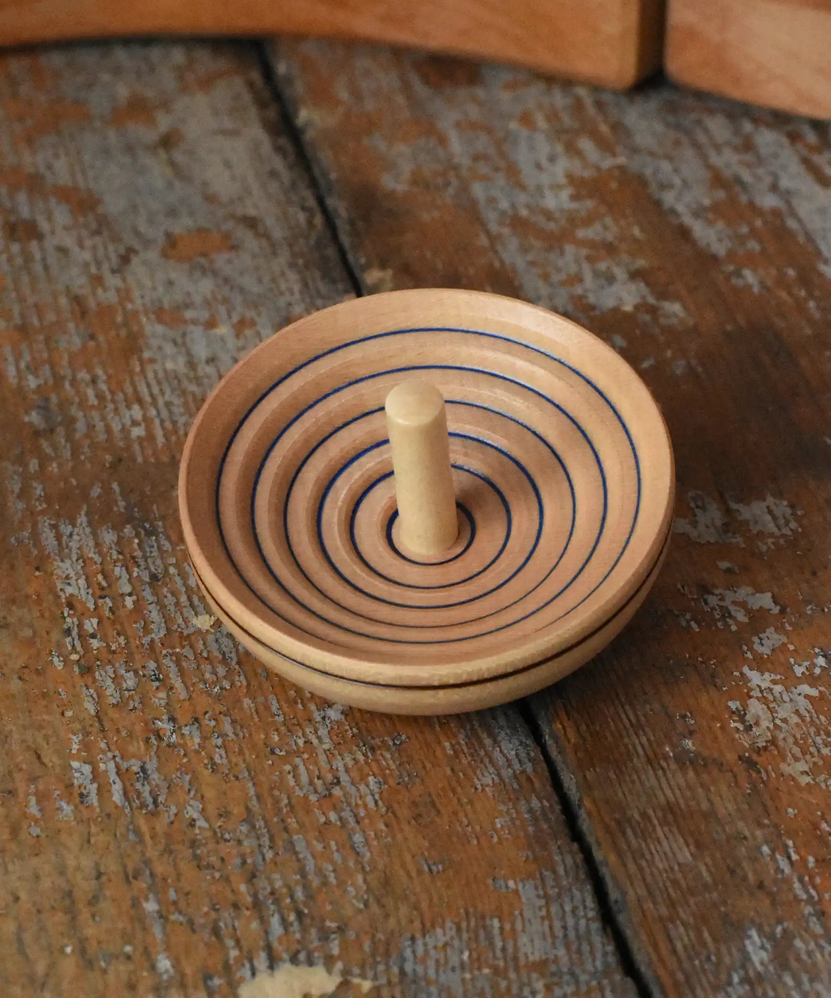 Mader UFO campanola spinning top in blue placed on a wooden desk in the Babipur playroom. 
