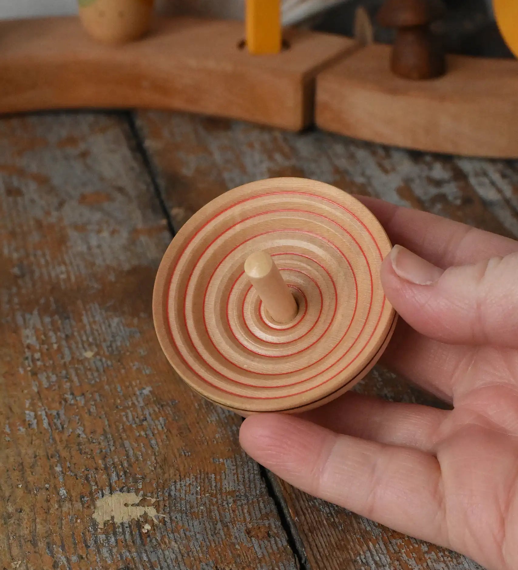 Mader UFO campanola spinning top in red in an adult's hand. 