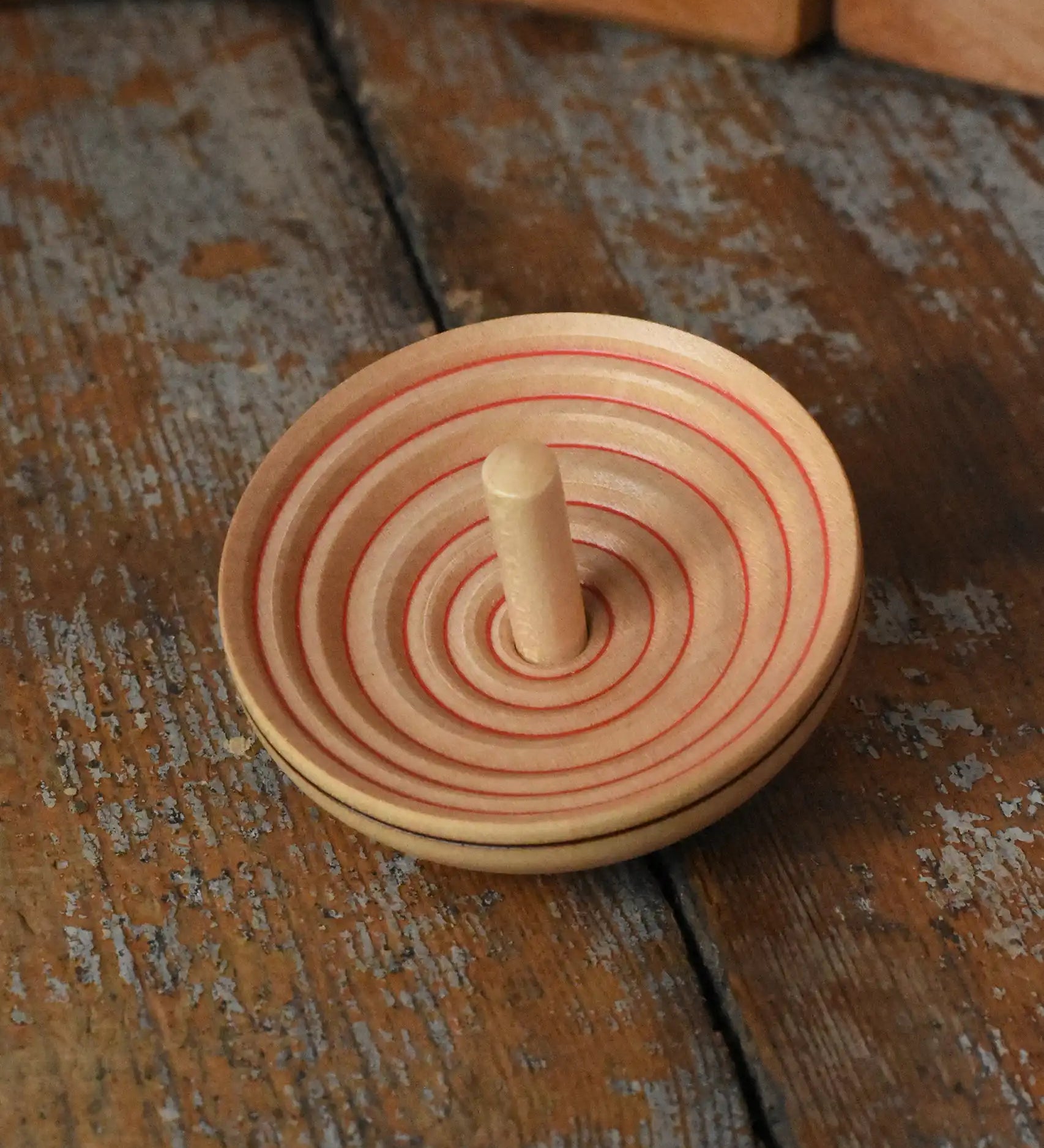 Mader UFO campanola spinning top in red placed on a wooden desk in the Babipur playroom. 
