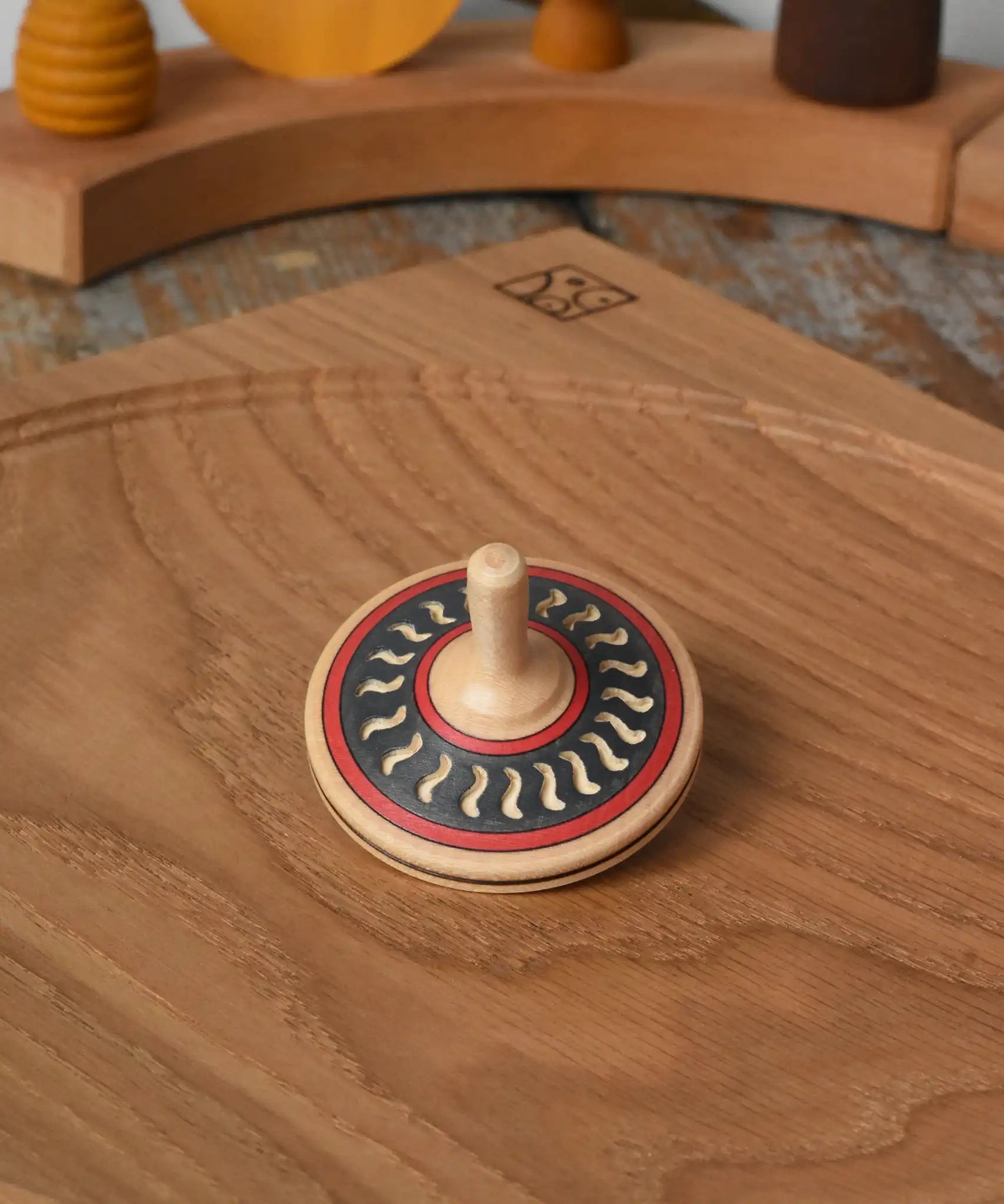 Mader Kreiselmanufaktur arabesk wooden finger spinning top placed on an oak spinning plate in the Babipur playroom.